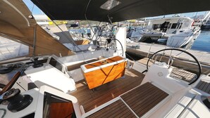 A boat deck with a wooden deck, a steering wheel, and a cabin area. - Sun-kissed Sailing Adventure in Split-Dalmatia, Croatia (Trogir)