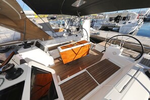 Ein Bootsdeck mit Holzboden, Steuerrad und einem Wohnbereich.
