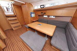 A compact, well-organized cabin with a wooden table, cushioned seating, and a small overhead shelf.