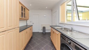 Een keuken met houten kasten, een ingebouwde oven, een spoelbak en een raam.
