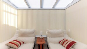 Een kamer met twee witte banken, een klein houten tafeltje en een plafond met dakramen.
