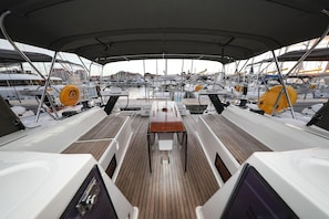 A covered deck with a central table, seating, and a view of the marina. - Sun-Kissed Sailing Adventure in Zadar, Croatia (Bibinje)