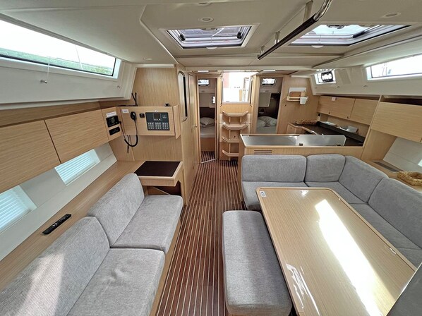 A compact RV interior with a kitchenette, seating area, and a small dining table. - Sun-Kissed Sailing Adventure in Northern Croatia (Punat)