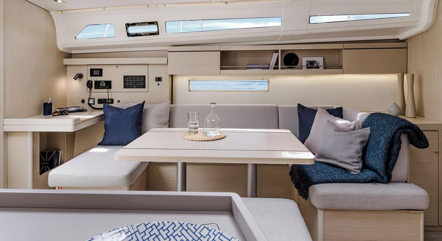 A compact, modern interior with a central table, cushioned seating, and built-in storage.