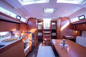 A compact kitchen with a dining area, a small table, and a bench. - Sun-Kissed Sailing Adventure in Istria, Croatia (Pula)