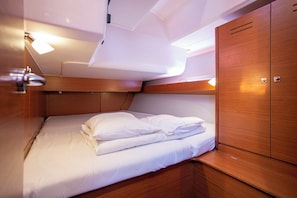 A compact cabin with a bed, wooden cabinetry, and overhead lighting. - Sun-Kissed Sailing Adventure in Istria, Croatia (Pula)
