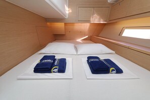 A compact cabin with a single bed, two pillows, and neatly folded towels on white sheets. - Sun-Kissed Sailing Adventure in Zadar, Croatia (Bibinje)