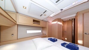 Una camera da letto con un letto, un armadio, una mensola a muro e un lucernario.