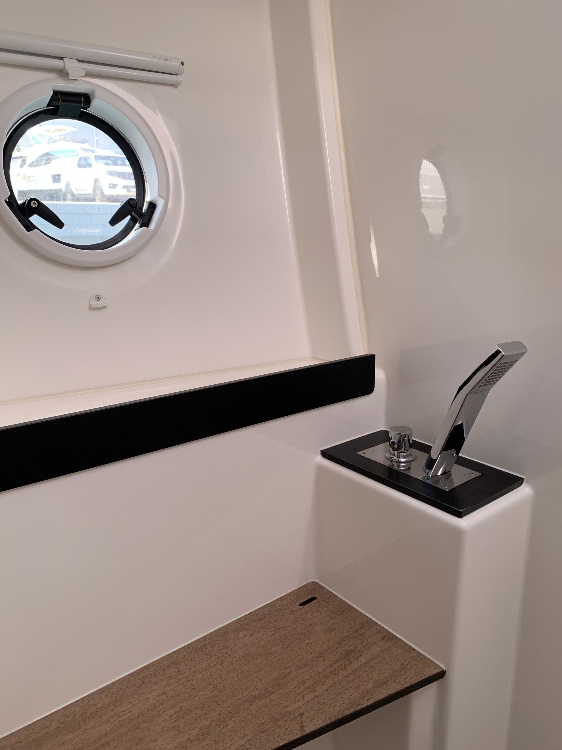 Ett badrum med ett runt fönster, en svart bänkskiva och en modern blandare.