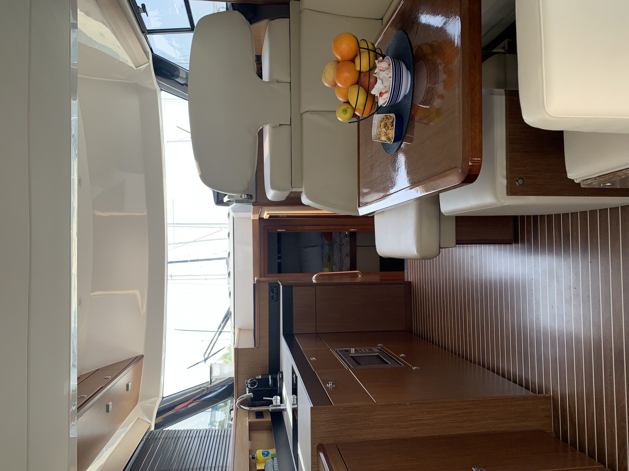 A compact kitchen area with a dining table, a fruit bowl, and a small refrigerator.