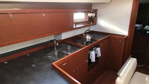 Una cucina compatta con lavello, fornelli e pensili.