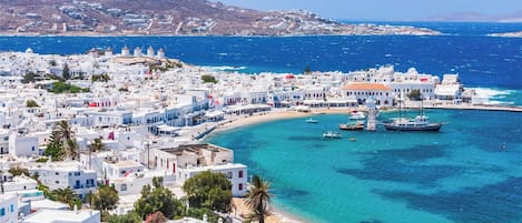 Un pueblo costero con edificios blancos, una playa y barcos en el agua.