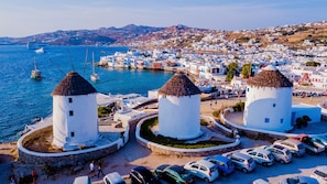 A coastal town with white-washed buildings, a harbor with boats, and a clear view of the sea.