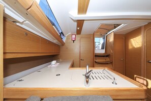 Een kleine badkamer met een wastafel, spiegel en houten kasten.