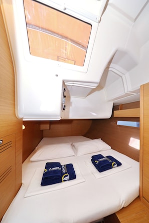 Een ruimtelijk hutje met een stapelbed, een klein raam en netjes opgevouwen handdoeken.