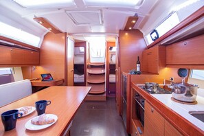 A compact kitchen with a dining area, a small seating space, and a window for natural light. - Sun-Kissed Sailing Adventure in Istria, Croatia (Pula)