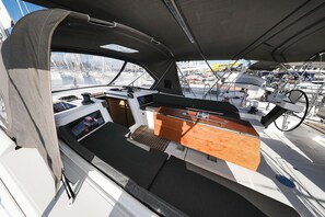 A boat's interior with a control station, seating area, and a view of other boats. - Sibenik Sun and Beach Sailing Extravaganza: A Croatian Coastal Adventure (Vodice)