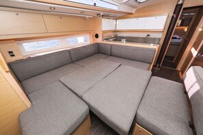 A compact interior with a sofa bed, a small kitchenette, and a window providing natural light. - Sibenik Sun and Beach Sailing Extravaganza: A Croatian Coastal Adventure (Vodice)