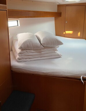 A compact bed with white linens and pillows, a wooden headboard, and a small bench at the foot of the bed. - Sun-Kissed Sailing Adventure in Zadar, Croatia (Bibinje)