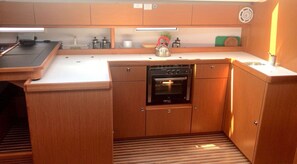 A compact kitchen with wooden cabinets, a built-in oven, and a kettle on the countertop.