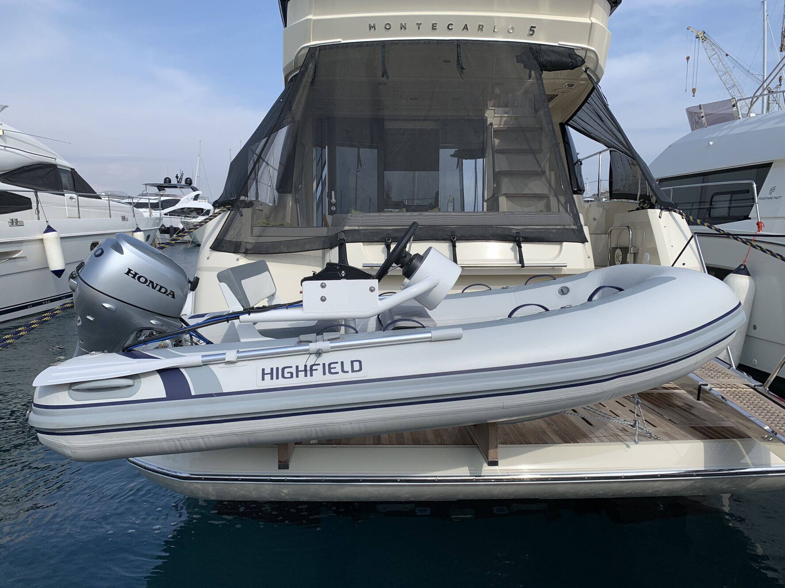 Un piccolo motoscafo chiamato 'HIGHFIELD' ormeggiato in una marina con altre imbarcazioni.