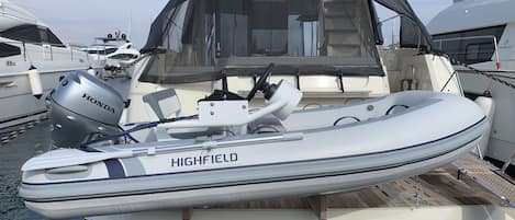 A small motorboat named 'HIGHFIELD' docked at a marina with other boats.