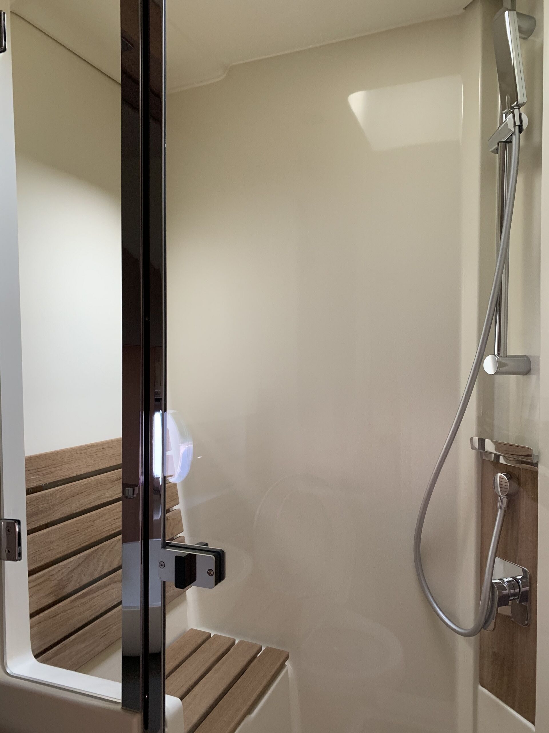 A modern bathroom with a shower, a bench, and a mirror.