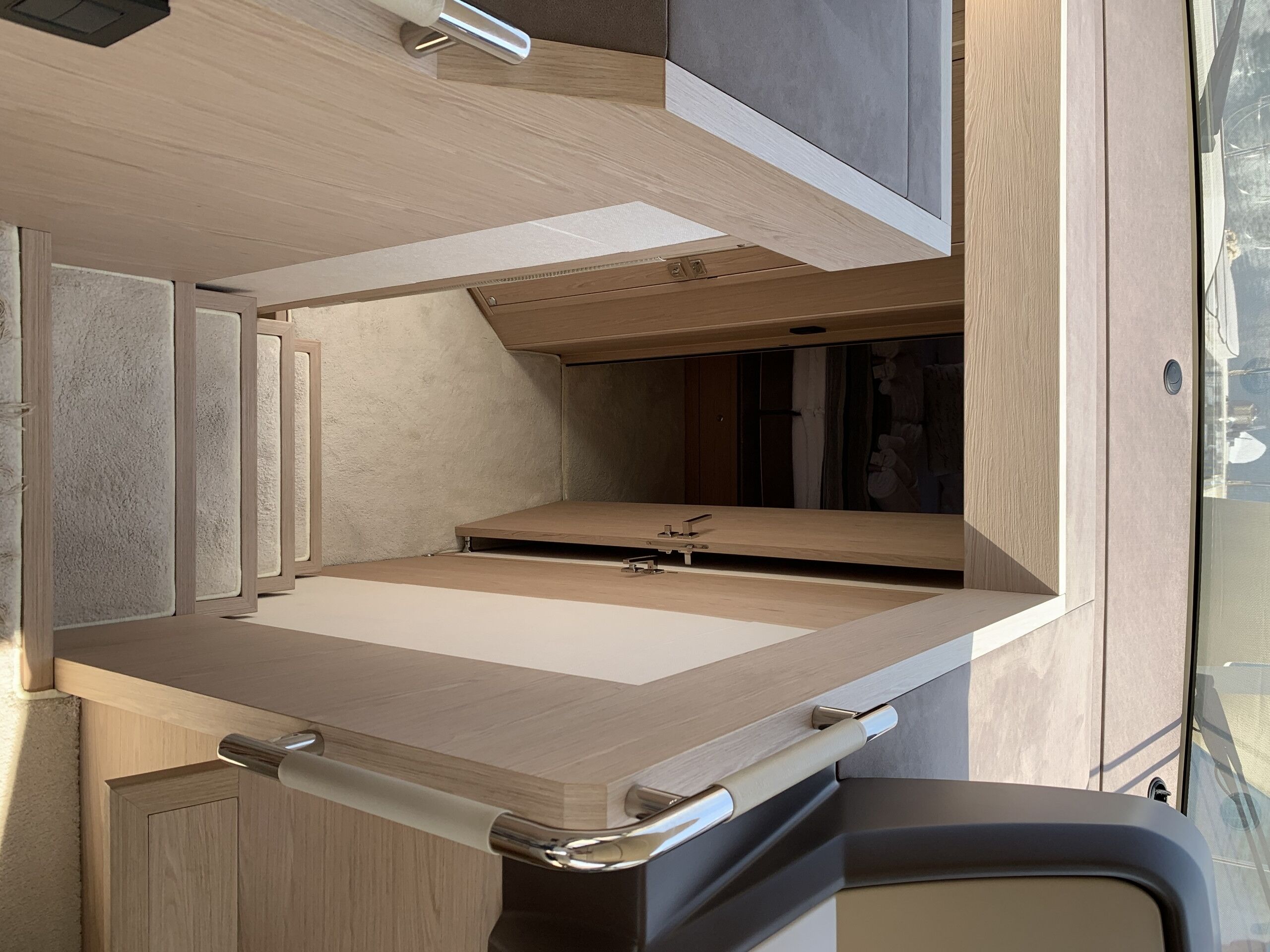 A compact, modern RV interior with a kitchenette, a sleeping area, and a small bathroom.