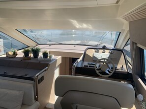 A boat's interior with a steering wheel, dashboard, and potted plants. - Sun-kissed Sailing Adventure in Split-Dalmatia, Croatia (Trogir)