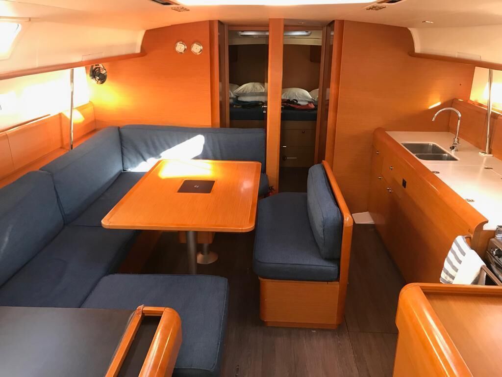 A compact cabin with a sofa, a small table, a bench, and a kitchenette area.