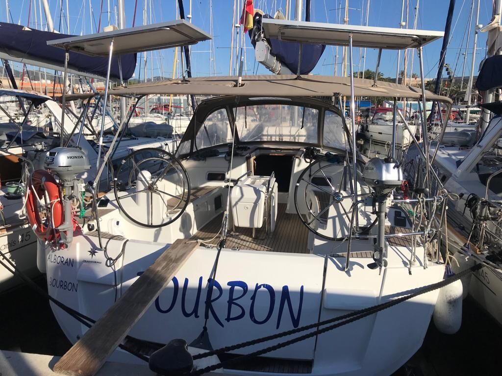 A boat named 'JURBON' docked at a marina with other boats, a steering wheel, and a Honda outboard motor.