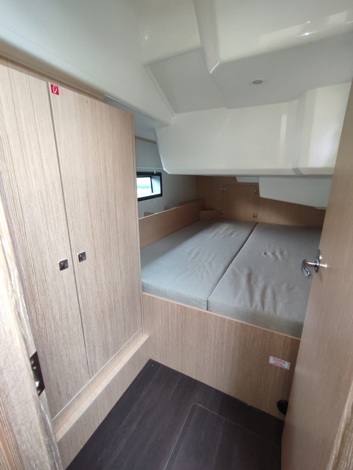 Un intérieur de camping-car compact comprenant un lit superposé, une petite fenêtre et une porte dotée d’une poignée.