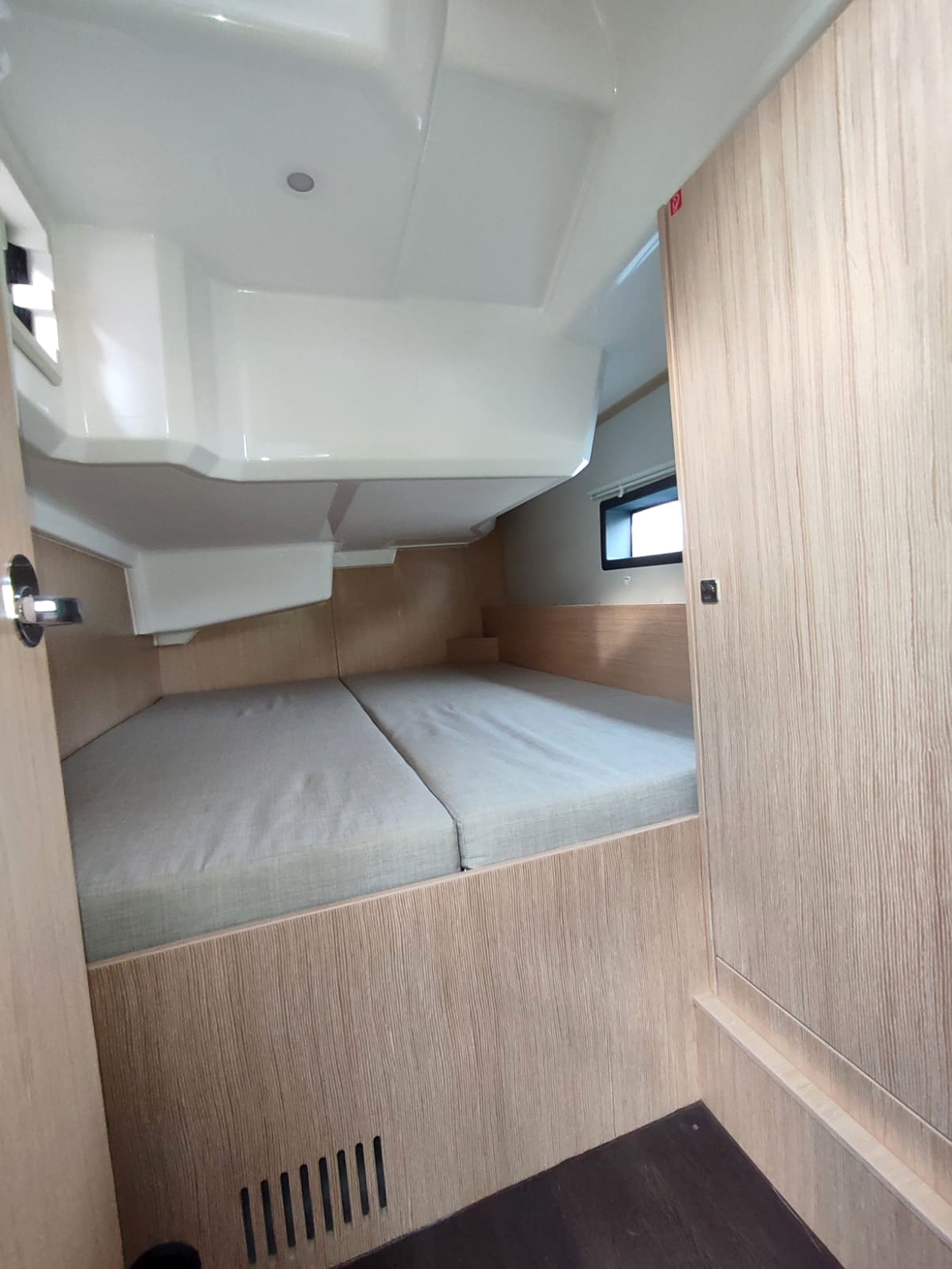 A compact interior with a bunk bed, a small window, and a door.
