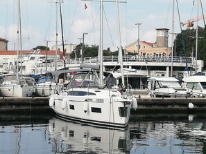 A marina with multiple boats docked, a building with a balcony, and a flag. - Sun-Kissed Sailing Adventure in Zadar, Croatia (Zadar)