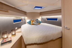 Un dormitorio moderno con una cama grande, lámparas de noche y un ventanal pequeño.