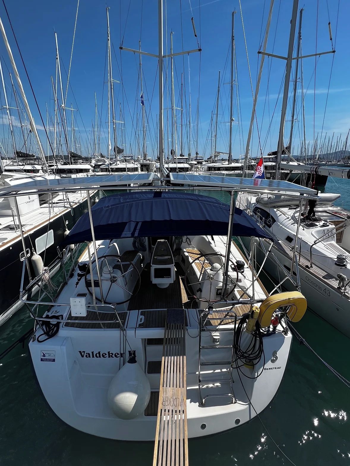 A marina with multiple sailboats docked, a covered deck area, and a boat named 'Valdeker.'