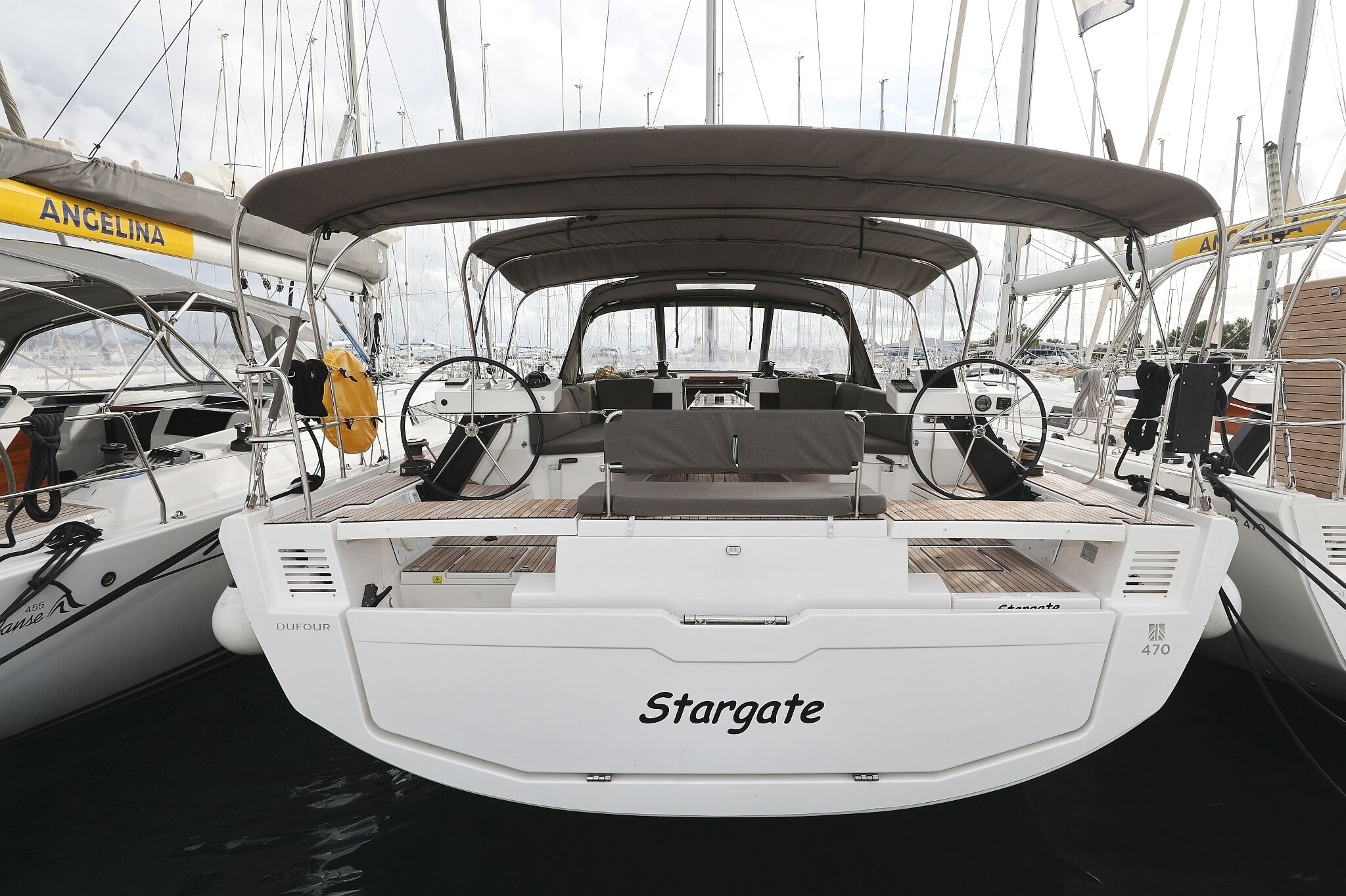 Een boot genaamd 'Stargate' met een overdekt dek, een stuurwiel en een zithoek.