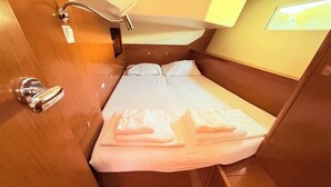 Una cabaña pequeña y luminosa con una cama individual, una mesita y una ventana que deja entrar luz natural.