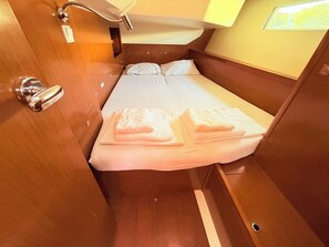 Ein gemütliches, gut beleachtetes Blockhaus mit einem Einzelbett, einem kleinen Tisch und einem Fenster, das für Tageslicht sorgt.