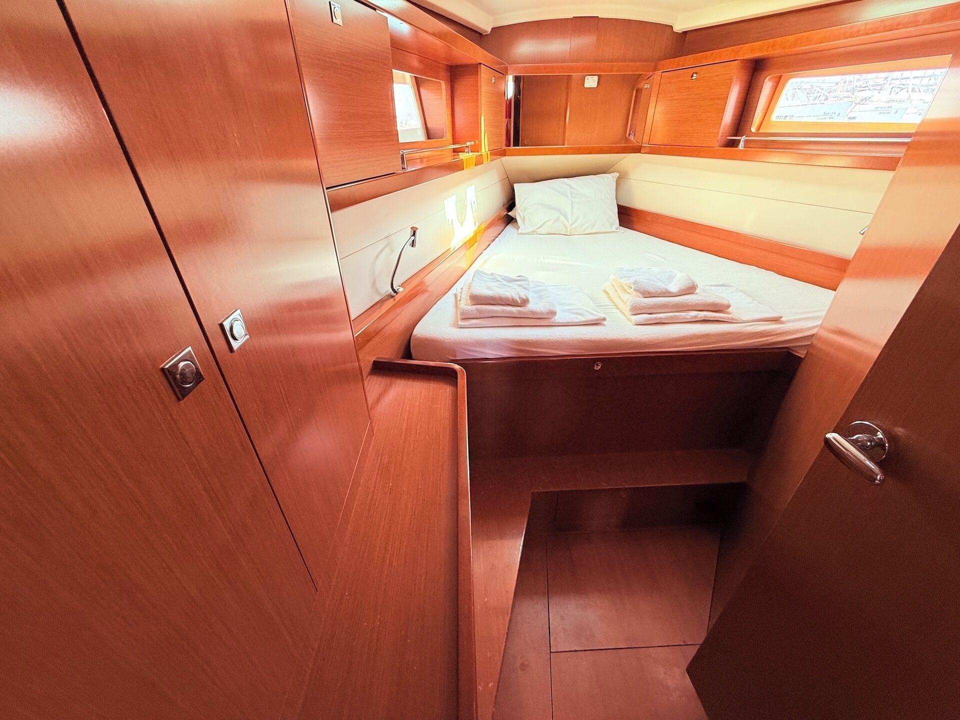 A compact cabin with a bed, a small window, and wooden cabinetry.