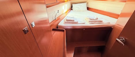 A compact cabin with a bed, a small window, and wooden cabinetry.