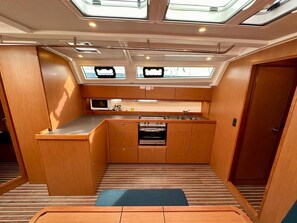 A compact kitchen with a microwave, stove, and sink, under skylights. - Sun-Kissed Sailing Adventure in Zadar, Croatia (Bibinje)