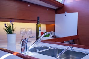 Una cocina con lavamanos de acero inoxidable, una planta en maceta y copas de vino.