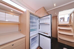 Eine kompakte, moderne Küche mit eingebauten Geräten, darunter ein Kühlschrank und ein Backofen, sowie einer kleinen Arbeitsfläche.