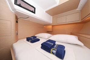 A compact, well-lit room with a bed, pillows, and neatly folded towels. - Sibenik Sun and Beach Sailing Extravaganza: A Croatian Coastal Adventure (Vodice)