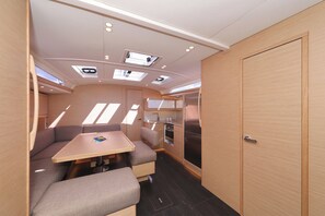 Een compact camperinterieur met een kitchenette, een eethoek met tafel en een bank, en een deur die naar een andere kamer leidt.