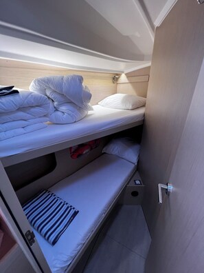 A bunk bed with white bedding, a small shelf with a red item, and a door with a handle. - Sun-Kissed Sailing Adventure in Zadar, Croatia (Bibinje)