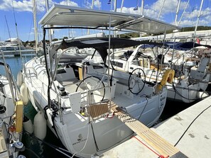 A sailboat docked at a marina with a covered cockpit, steering wheel, and various navigational equipment. - Sun-Kissed Sailing Adventure in Zadar, Croatia (Bibinje)