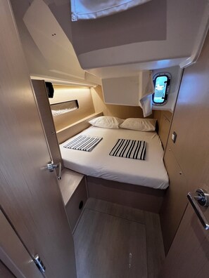A compact, well-lit cabin with a bed, a small window, and a door. - Sun-Kissed Sailing Adventure in Zadar, Croatia (Bibinje)