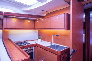 A compact kitchen with wooden cabinets, a sink, and a stove. - Sun-Kissed Sailing Adventure in Istria, Croatia (Pula)